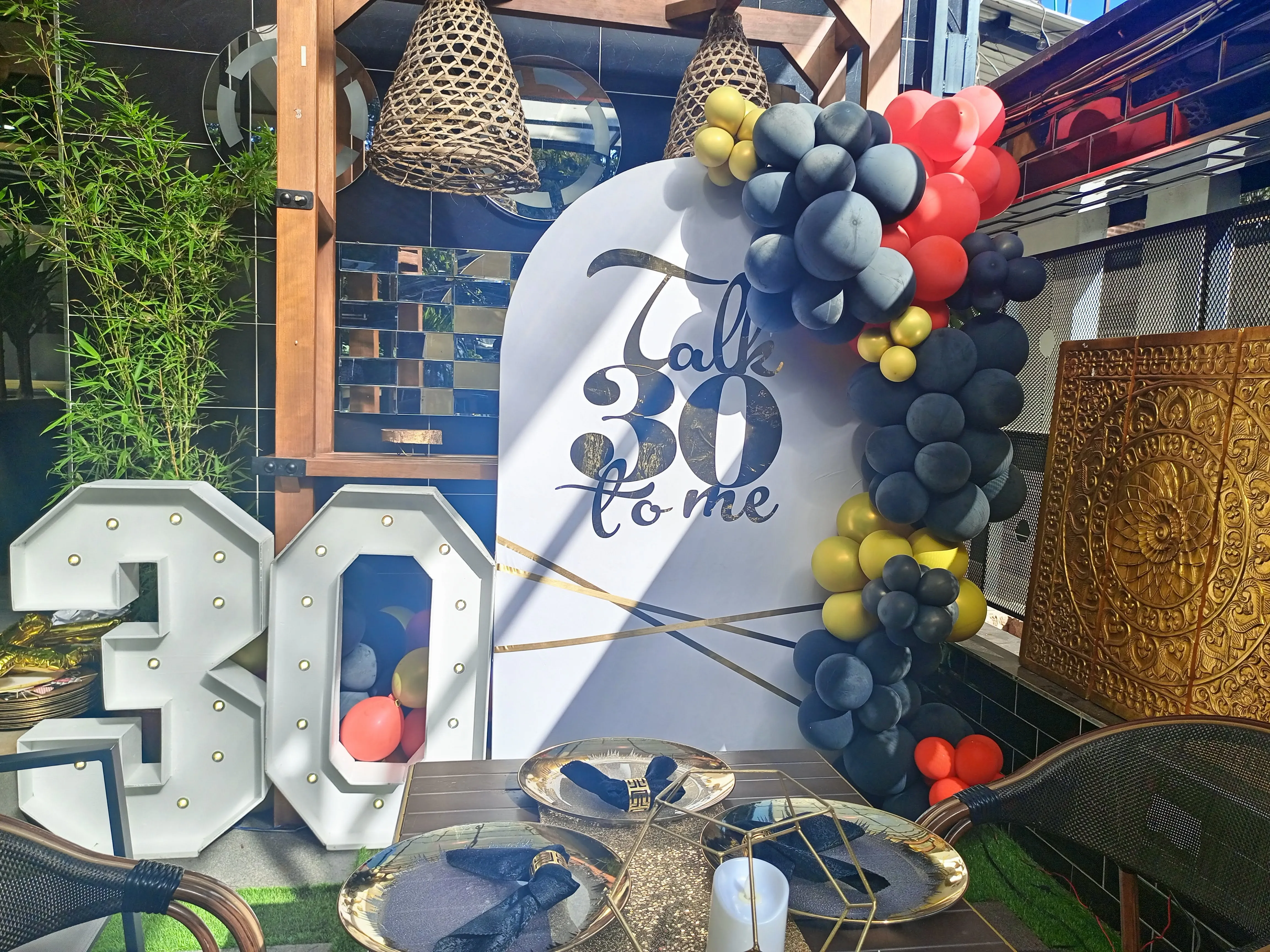 Stylish 30th birthday corner with navy, red and gold balloons, marquee 30 letters and gold tableware