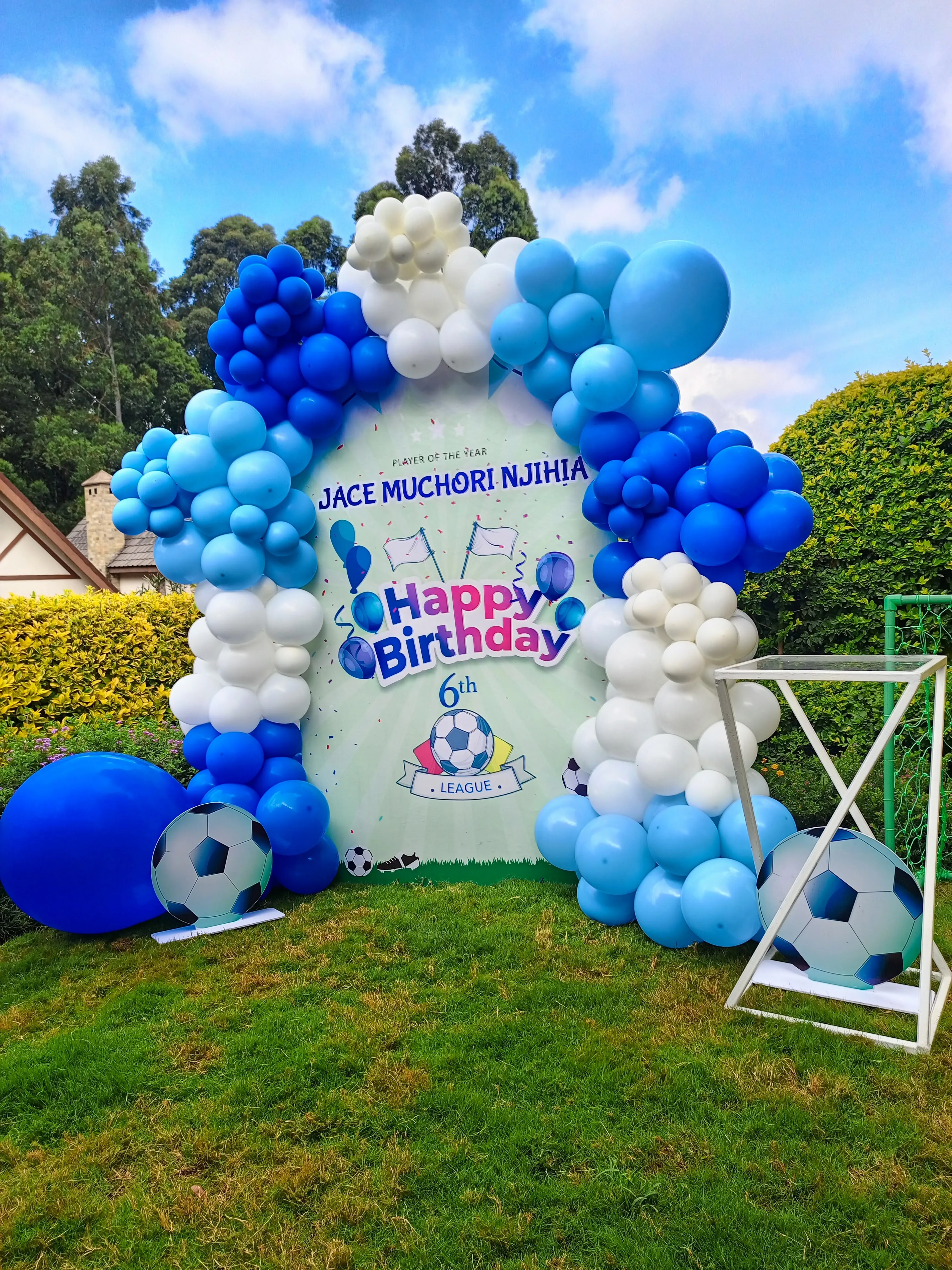 Football-themed birthday balloon arch in blues and white on a sunny lawn