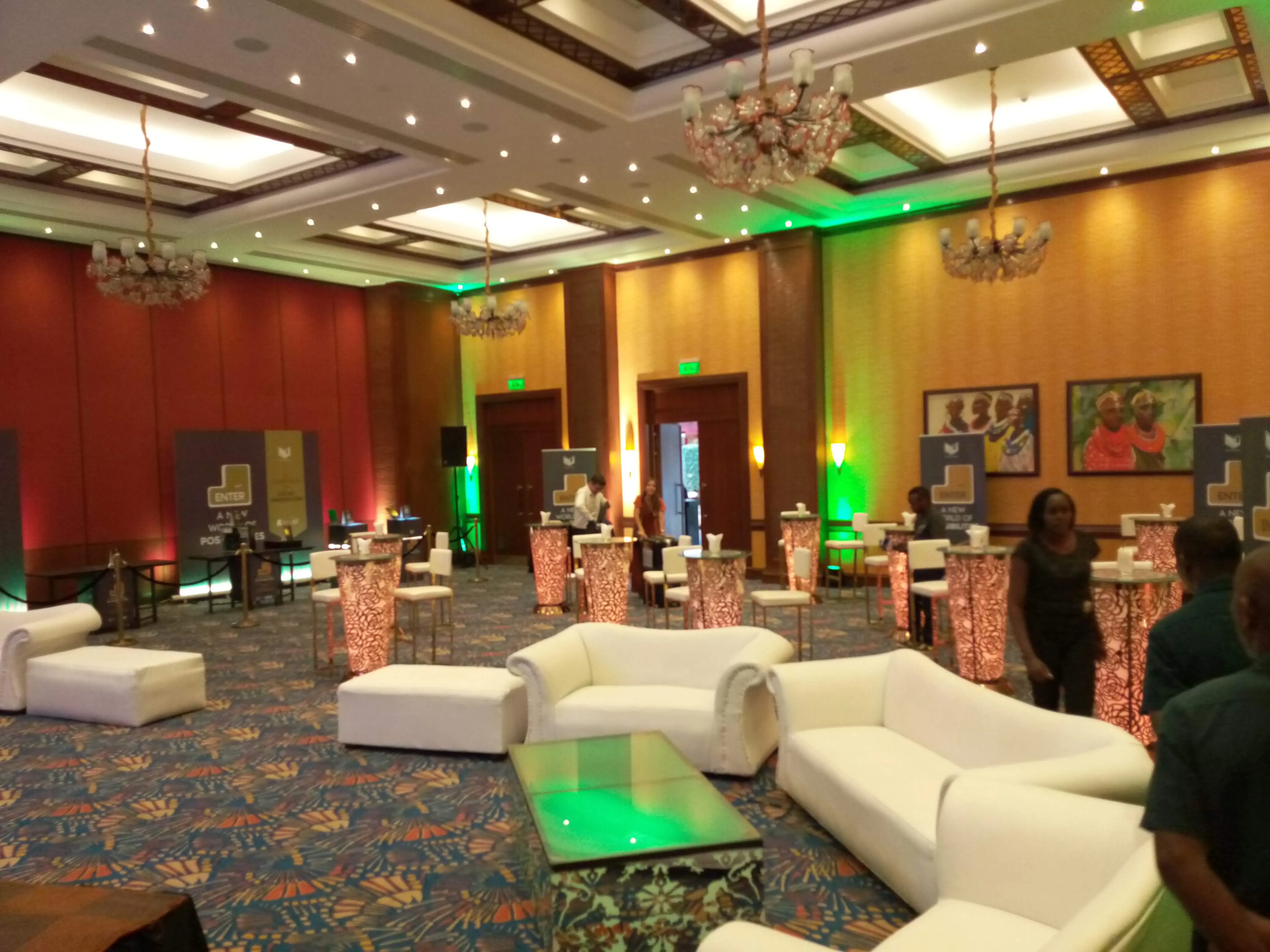 Banquet hall with gold-sashed white chairs facing a stage with ENTER conference branding