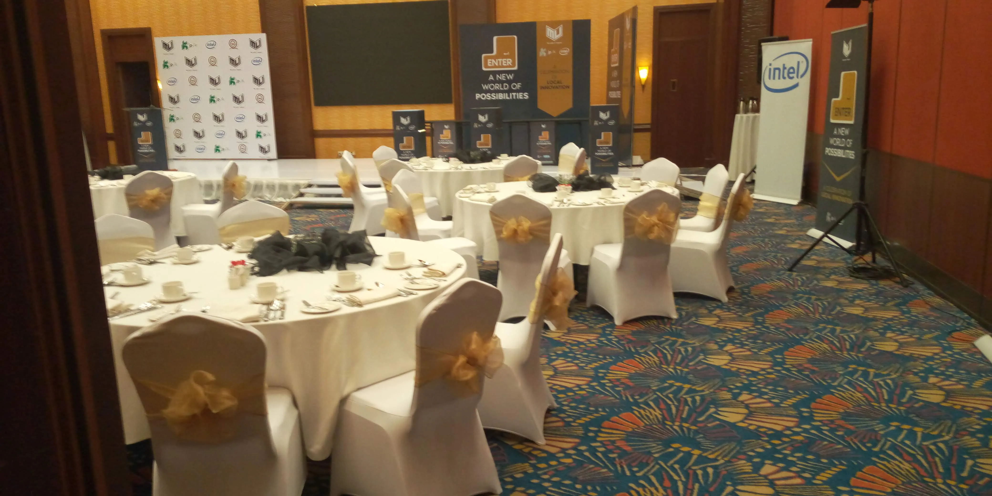 Conference stage with ENTER set pieces, projection screen and stacked dice props in a carpeted ballroom