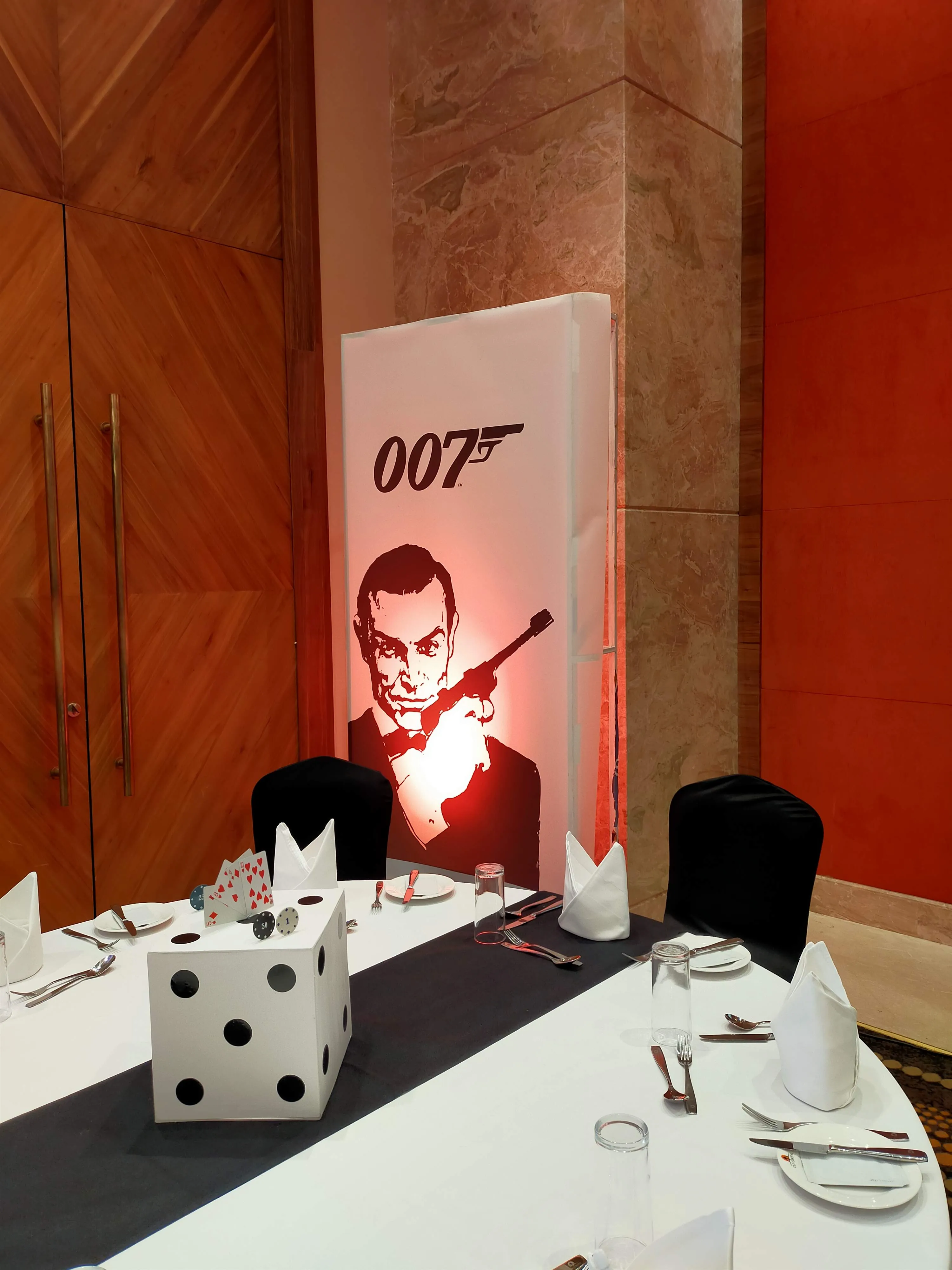 007 casino-themed gala ballroom with oversized dice and a spotlit Bond standee