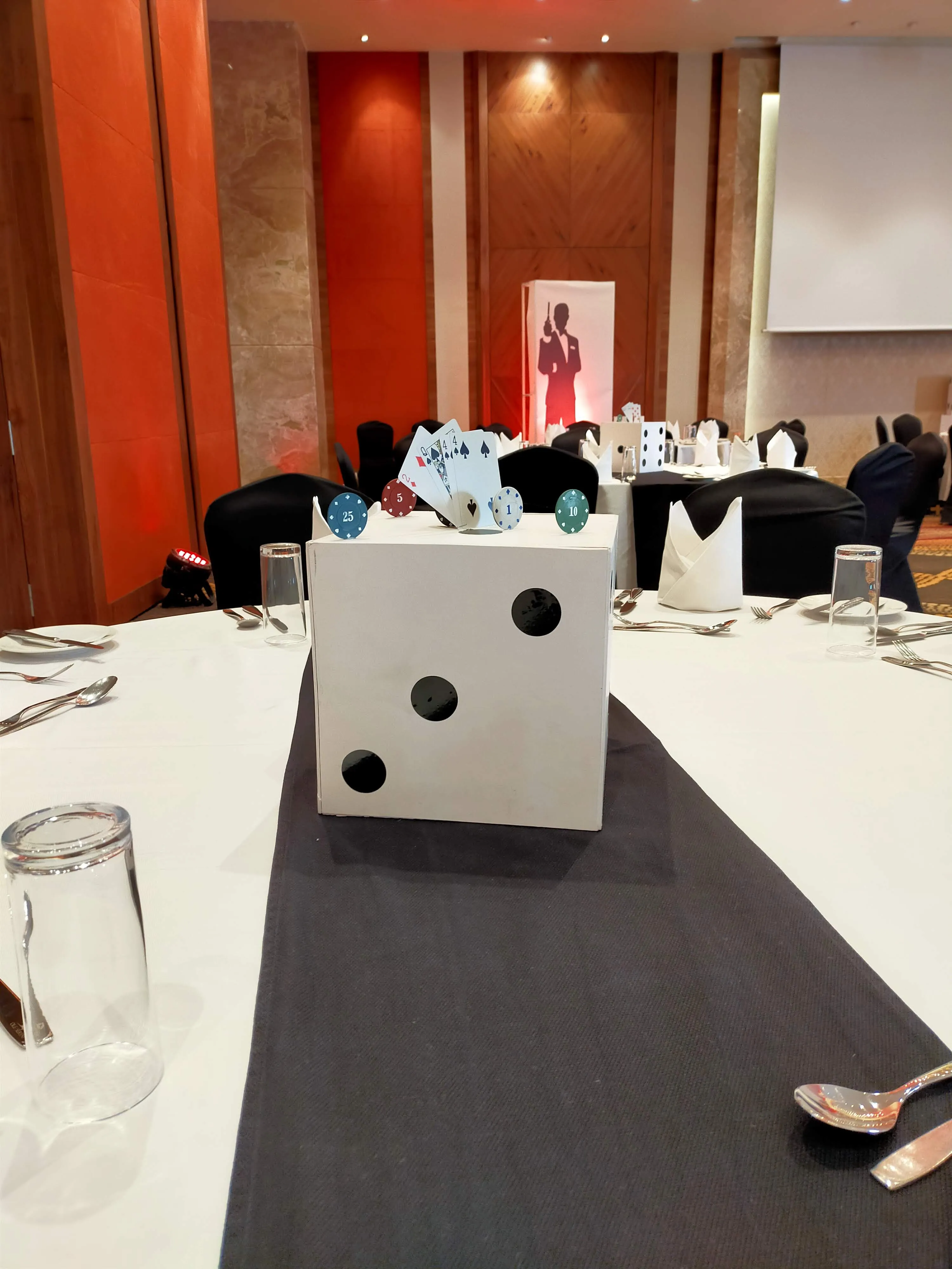 Dice centrepiece topped with playing cards and casino chips on a 007 themed dining table