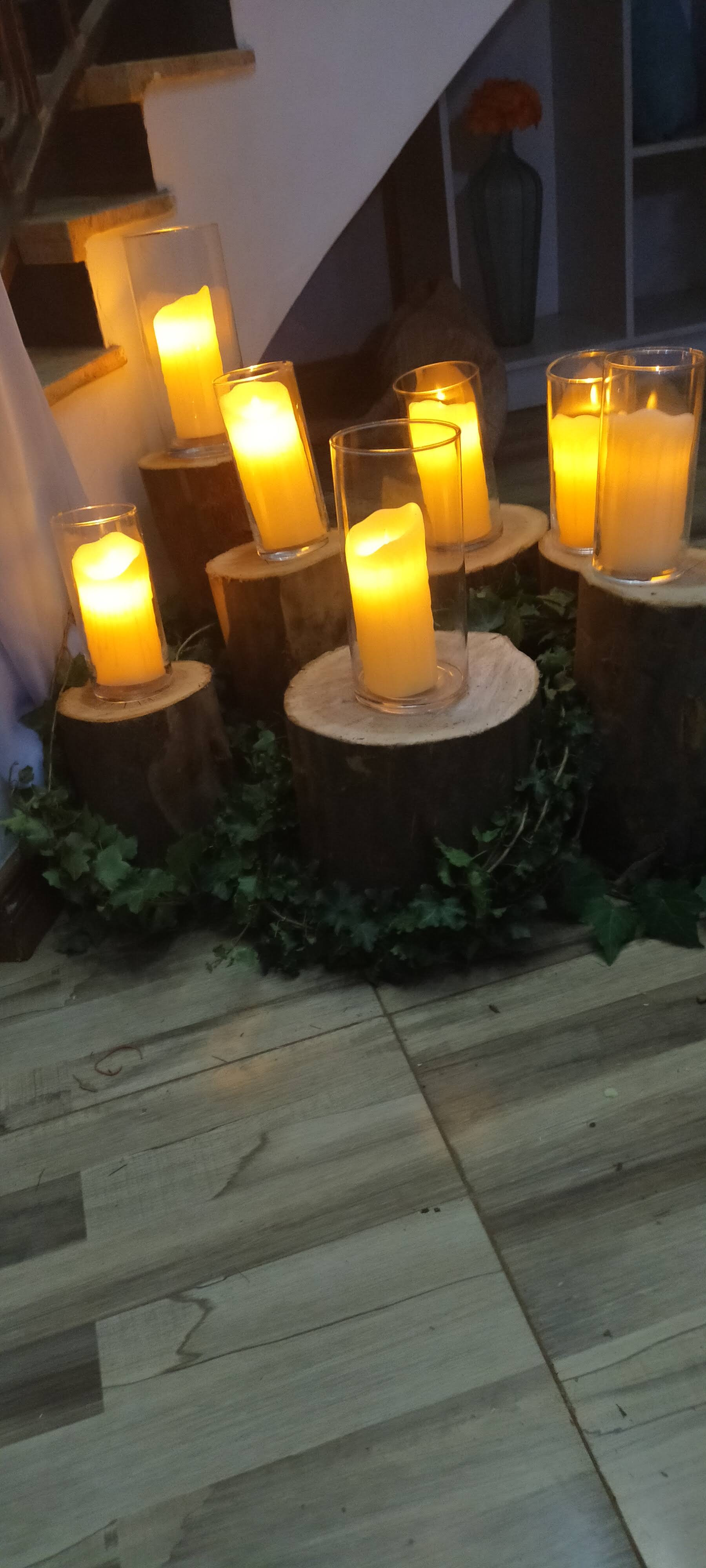 Pillar candles in glass on log rounds, wrapped in ivy, at the foot of a staircase