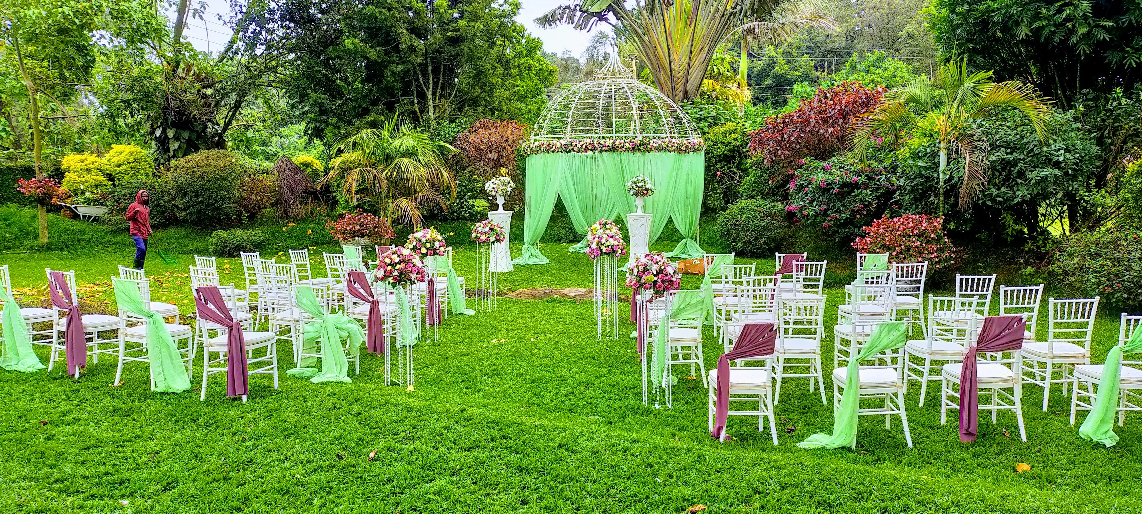 Garden ceremony with a domed gazebo draped in mint green, white chiavari chairs and floral aisle stands